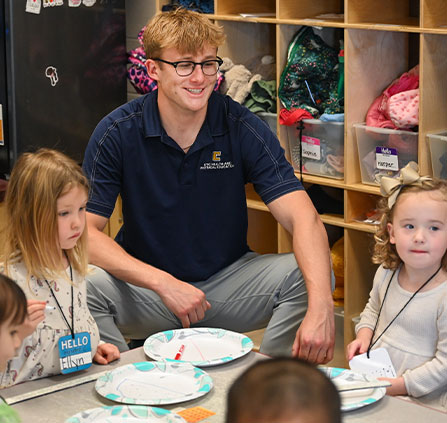 Photo of a UTC student and young students. Link to Tangible Personal Property.