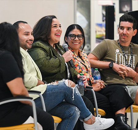 Photo of a person holding a microphone with a group of people. Link to Gifts of Real Estate.